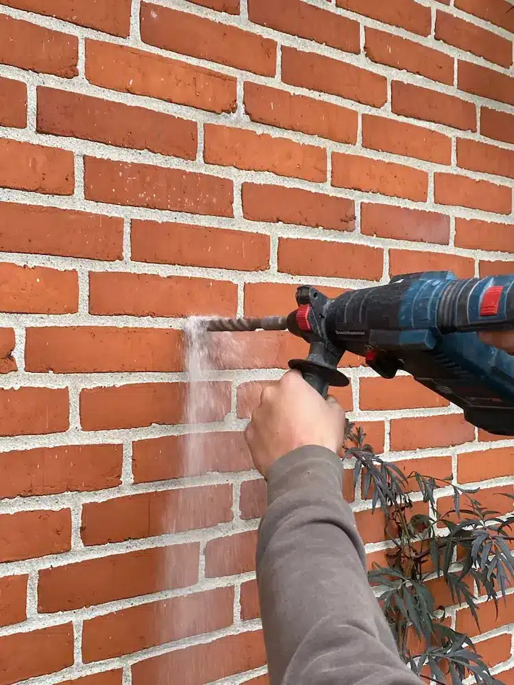 Der bores et hul i fugen på en murstensfacade inden hulmursisolering